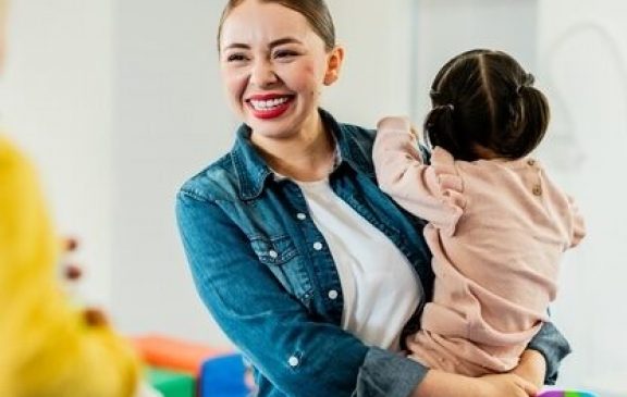 Young mother carrying baby daughter and talking to other parents at parents support group